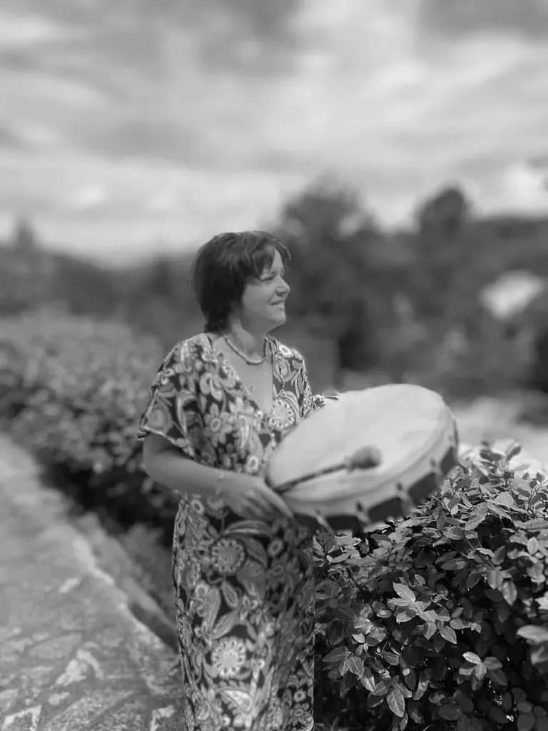 Natalia joue du tambour chamanique dans un jardin